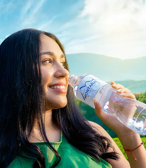 Mujer tomando Agua de la Montaña con las montañas de fondo